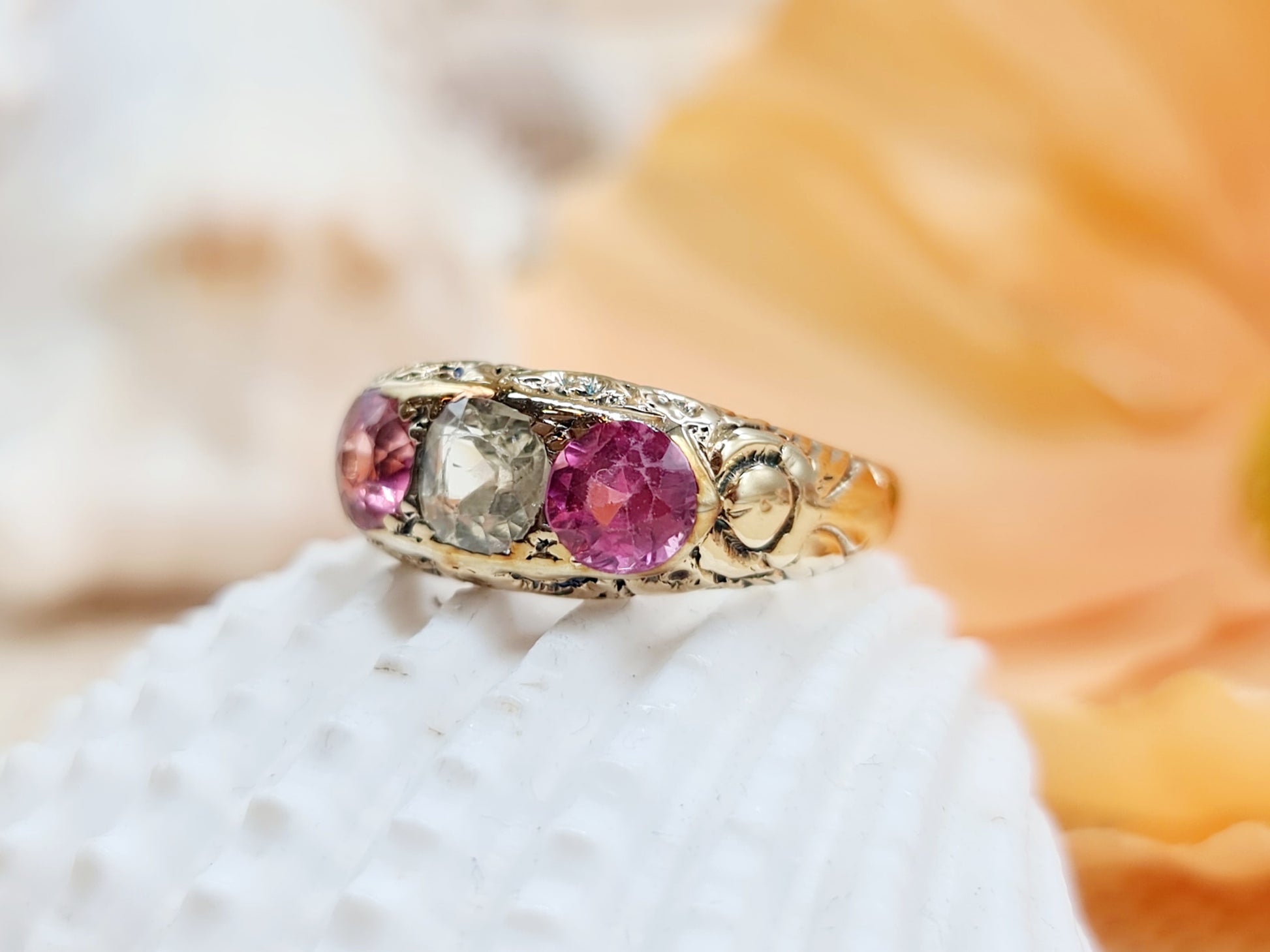 Antiker Spinell Ring aus 585 Gelbgold mit fein verzierter Ringschiene und einem zentralen weißen Spinell umarmt von zwei leuchtend pinken Spinellen.