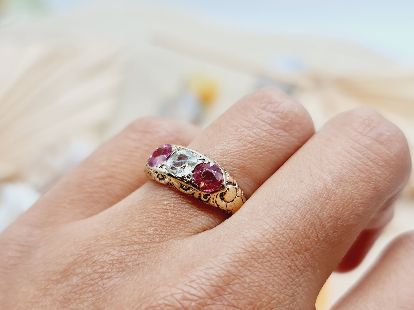 Antiker Spinell Ring aus 585 Gelbgold mit fein verzierter Ringschiene und einem zentralen weißen Spinell umarmt von zwei leuchtend pinken Spinellen.